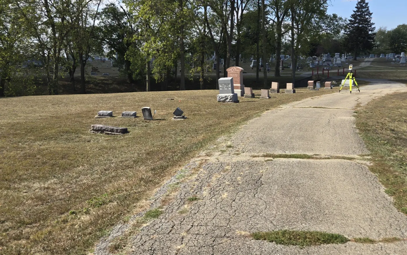 Field scientist operating a total station in a cemetery